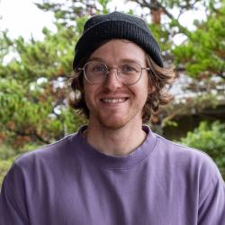 A young man wears a knit cap and glasses.