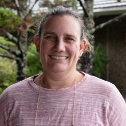 A woman with hair pulled back, smiles.