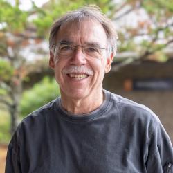 A man with gray, thinning hair wearing wire rimmed glasses and a mustache.