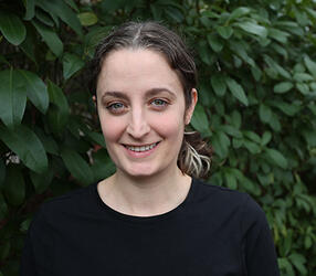 A woman with her hair pulled back wearing a black tshirt.